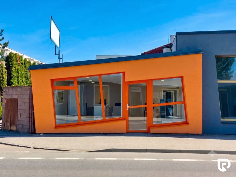 Oranžová fasáda obchodních prostor na Zlatovské ulici v Trenčíně s velkými skleněnými okny.