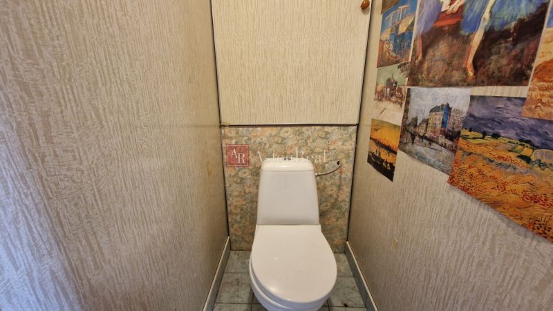 Kompaktní toaleta v 2pokojovém bytě se vzorovanými stěnami a dlažbou.