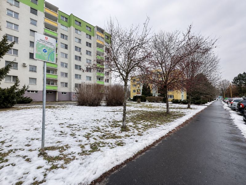 Zasněžená ulice Novozámocká ve Zvolenu s komerčními pozemky a bytovými domy.