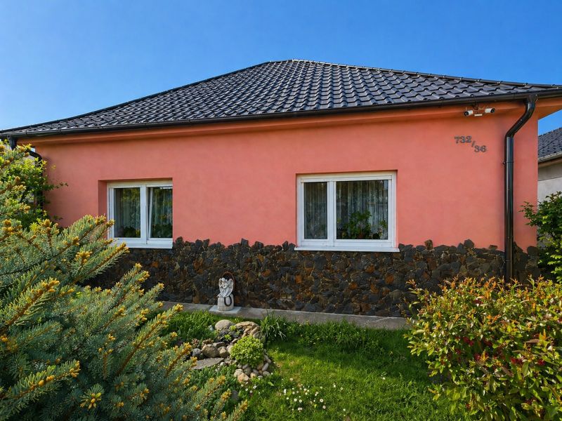 Rodinný dům na Nové cestě v Jelce, okres Galanta, má růžovou fasádu a taškovou střechu.