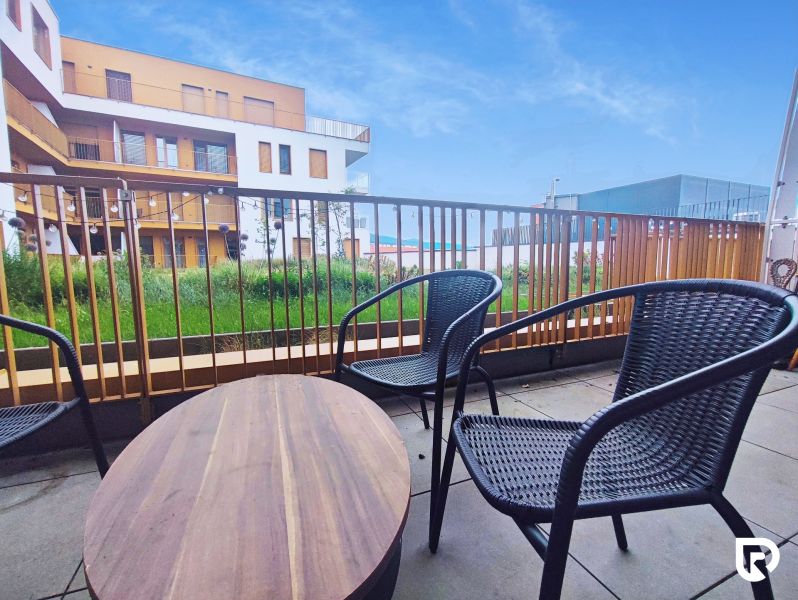 Balkon s ratanovým posezením a výhledem na architekturu Piaristické ulice v Nitře.