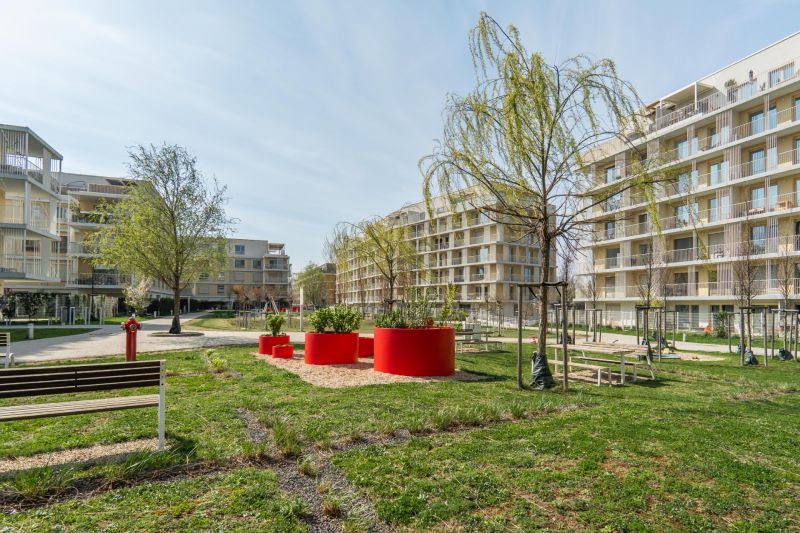 Exteriér bytových domů v Bratislavě - Ružinově se stromy a lavičkami.