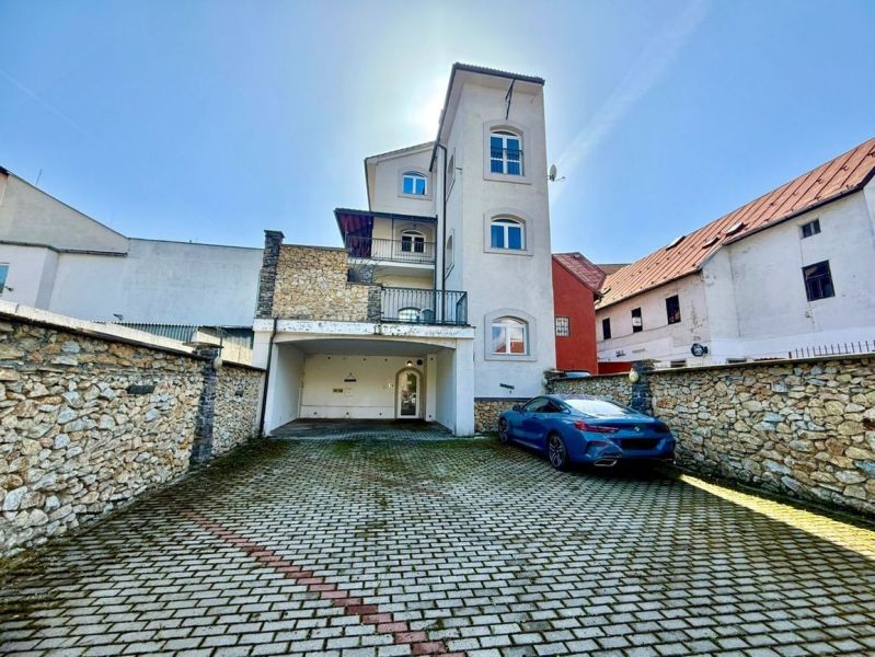 Budova na Dolní ulici 28 v Banské Bystrici s parkovištěm a kamennou zdí.