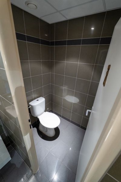 Koupelna s toaletou, dlaždicemi a šedou podlahou s keramickým dekorem.