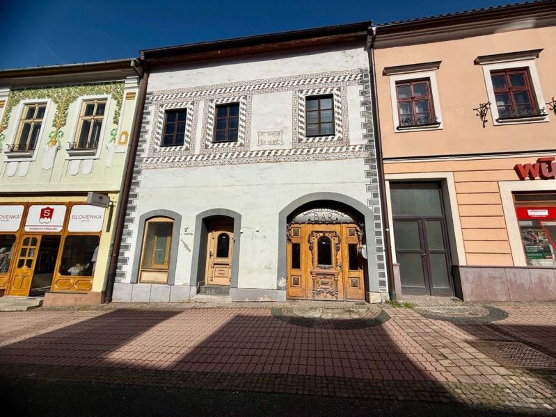 Ulice Dolná v Banské Bystrici zobrazuje historické budovy s obchody a barem.