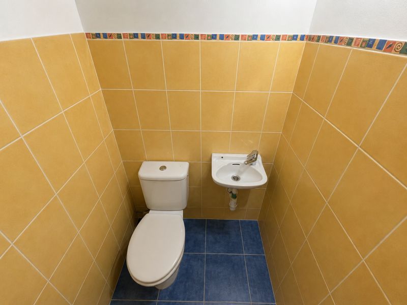 Toaleta s umyvadlem v koupelně s barevnými obklady v 2-pokojovém bytě.