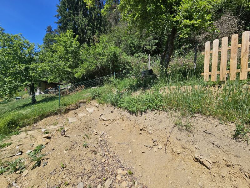 Strmý svah s kopcem v Budatíně u chaty, obklopený zelení a stromy.