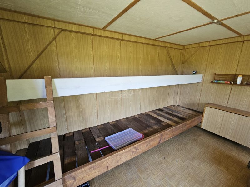 Interiér chaty s palandou, podlahou s dřevěným dekorem a dřevěnou stěnou.