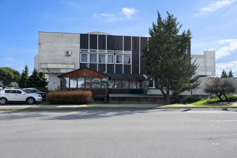 Exteriér gastro prostorů v Žiaru nad Hronom, obklopený stromy a zaparkovanými auty.