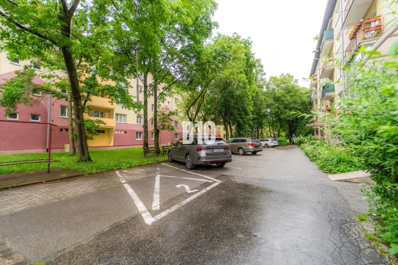 Parkoviště s auty a obytnými domy obklopené zelení v Martině.