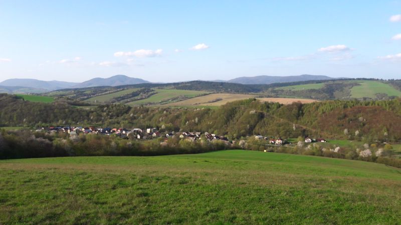 Pohled na zemědělské a lesní pozemky v Bogliarce s kopcovitým horizontem a vesnicí.