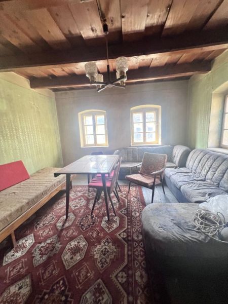 Obývací pokoj v rodinném domě s dřevěným stropem, sedačkou a vzorovaným kobercem.