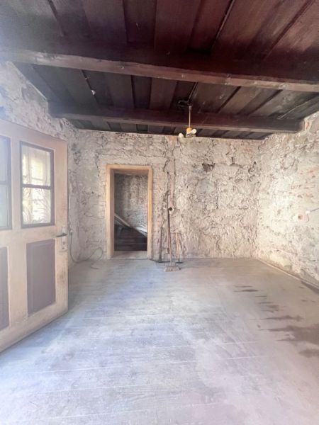 Rustikální místnost v rodinném domě s kamennými stěnami a podlahou s dřevěným dekorem.