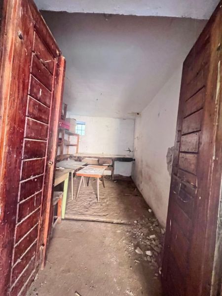 Dřevěné dveře vedou do místnosti rodinného domu s nábytkem a surovou podlahou.