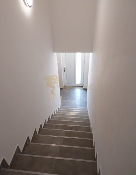Schodiště ve 4-pokojovém bytě s dlažbou a bílými stěnami.