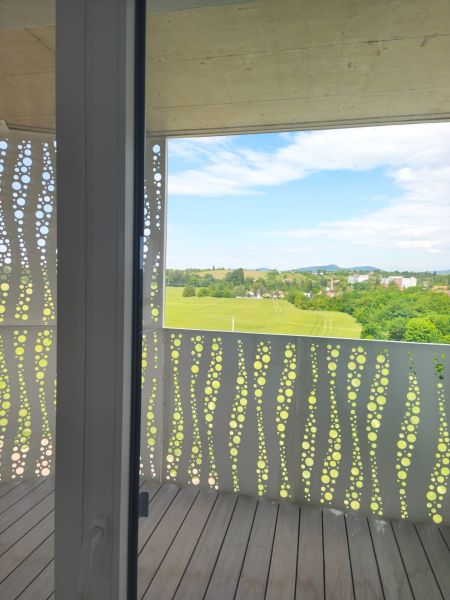 Balkon s panoramatickým výhledem a podlahou s dřevěným dekorem v 2-pokojovém bytě.