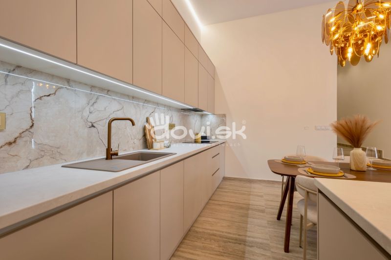 Kuchyně s elegantní pracovní deskou, moderním dřezem a dekorativním osvětlením v rodinném domě.