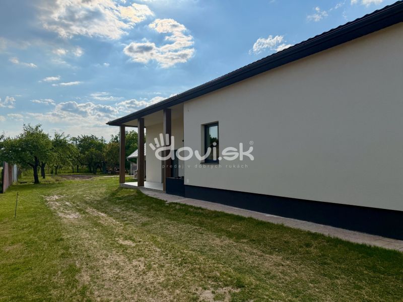 Exteriér rodinného domu v Zemplínskej Širokej obklopený trávníkem a stromy.