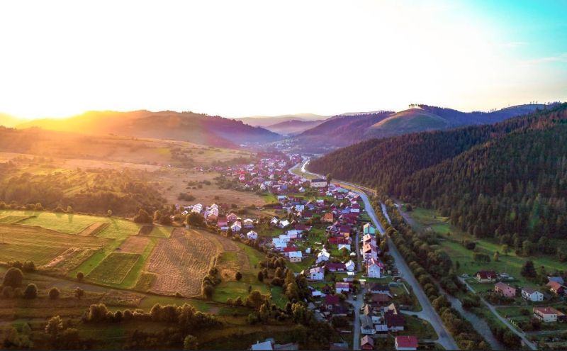 Krajina v okolí Nové Bystrice se zemědělskými a lesními pozemky při západu slunce.