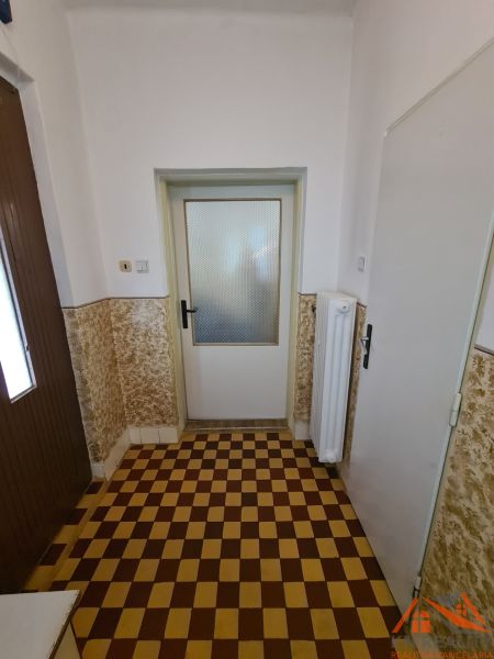 Dlažba se šachovnicovým vzorem v interiéru rodinného domu s bílými stěnami.