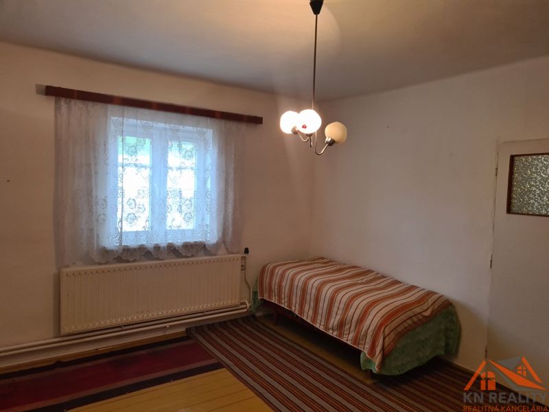 Jednoduchý pokoj s postelí a oknem, rodinný dům, koberec a závěsy.