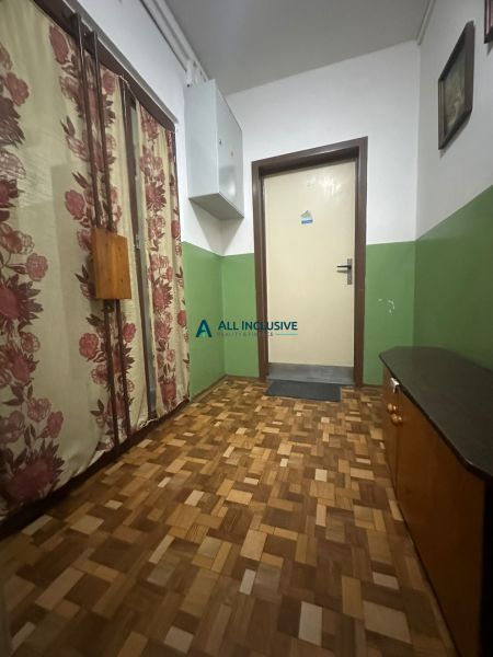 Chodba 2pokojového bytu s podlahou s dřevěným dekorem a květinovými závěsy.