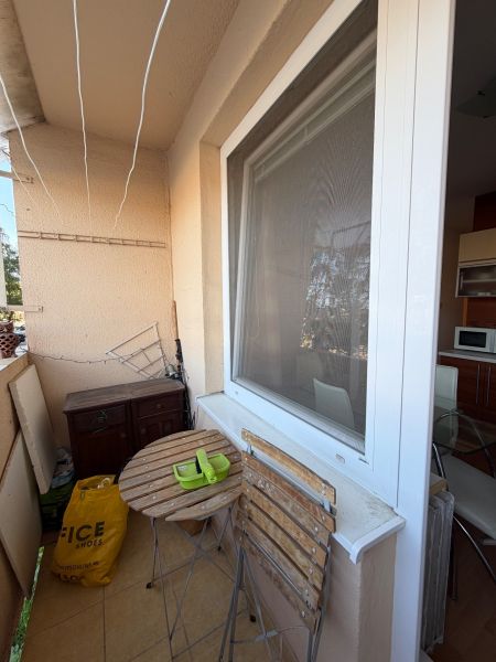 Balkon 3pokojového bytu s dřevěným stolem a židlemi, vedle kuchyňského okna.
