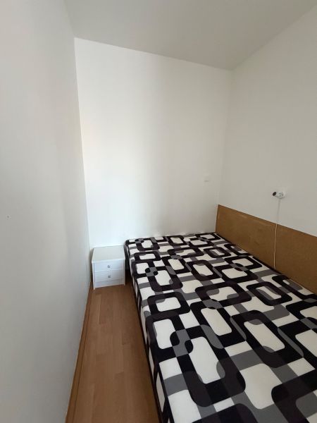 Jednoduchý pokoj ve 3pokojovém bytě s postelí a podlahou s dřevěným dekorem.