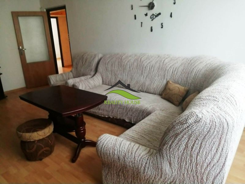 Obývací pokoj v 3-pokojovém bytě s rohovou sedačkou a podlahou s dřevěným dekorem.