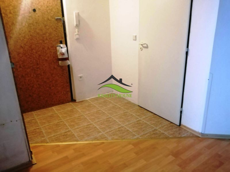 Chodba 3pokojového bytu s dlažbou a podlahou s dřevěným dekorem.