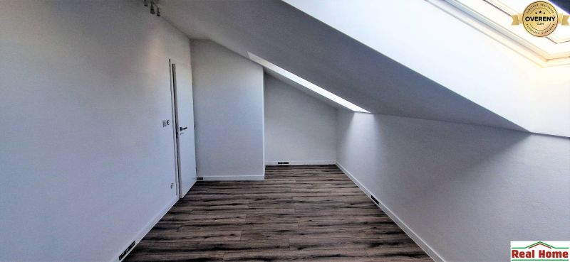 Podkroví v rodinném domě s podlahou s dřevěným dekorem a střešním oknem.