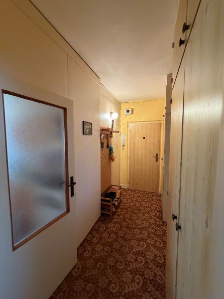 Chodba 2-pokojového bytu s vestavěnými skříněmi a kobercovou podlahou.