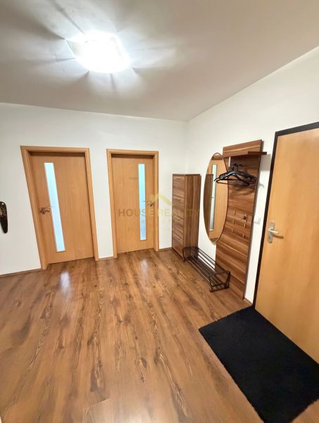 Předsíň se skříní, věšákem a podlahou s dřevěným dekorem ve 4-pokojovém bytě.
