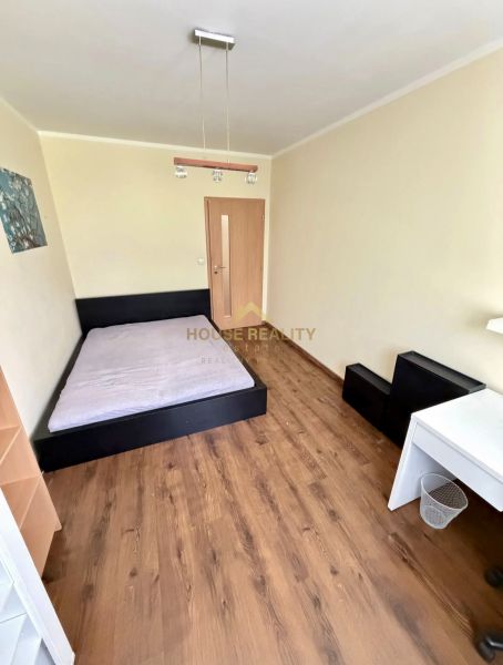 Ložnice se světlým interiérem, postelí a podlahou s dřevěným dekorem ve 4pokojovém bytě.