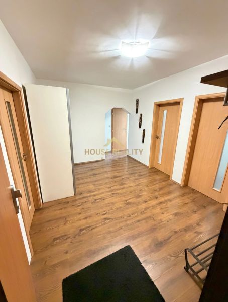 Předsíň 4pokojového bytu s podlahou s dřevěným dekorem a dřevěnými dveřmi.
