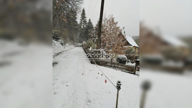 Zasněžená ulice v Horních Otrokovicích s rodinným domem a oplocením.