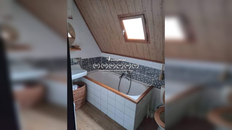 Koupelna s vanou a šikmým stropem, dřevěný dekor, mozaikový obklad, okno.