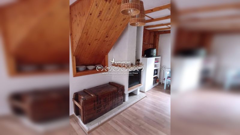 Interiér rodinného domu s krbem, podlahou s dřevěným dekorem a úložným prostorem.