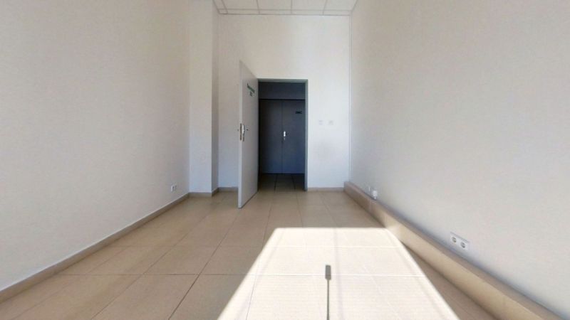 Interiér kanceláře s bílými stěnami a světlým keramickým obkladem podlahy.