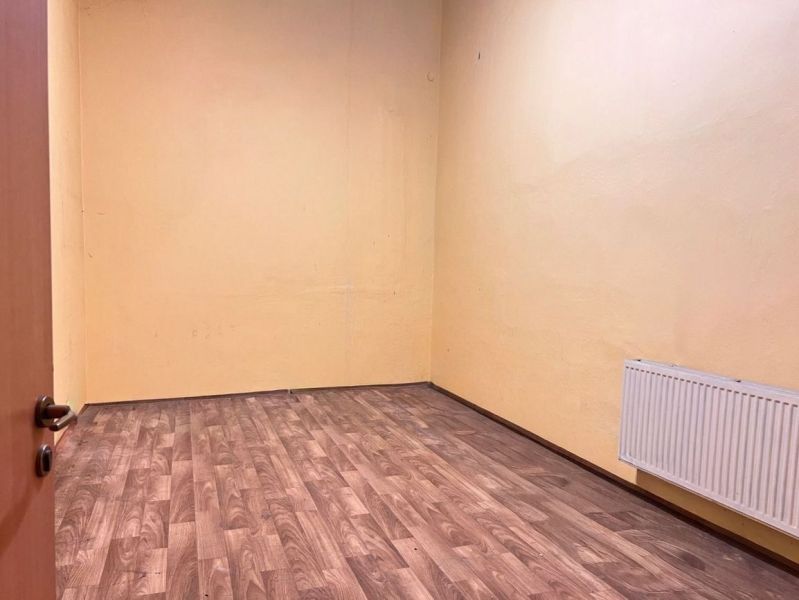 Místnost s podlahou s dřevěným dekorem, žlutými stěnami a radiátorem ve skladech a halách.