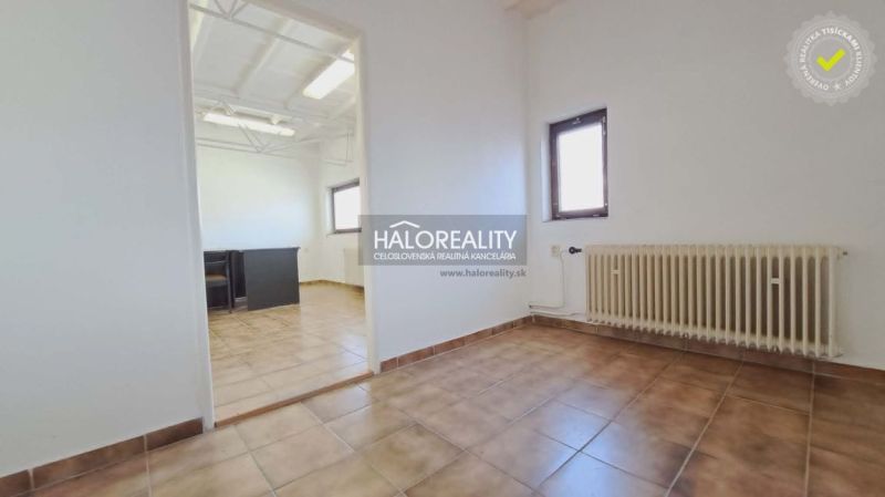 Kanceláře s dlaždicovou podlahou, radiátorem a přirozeným světlem.