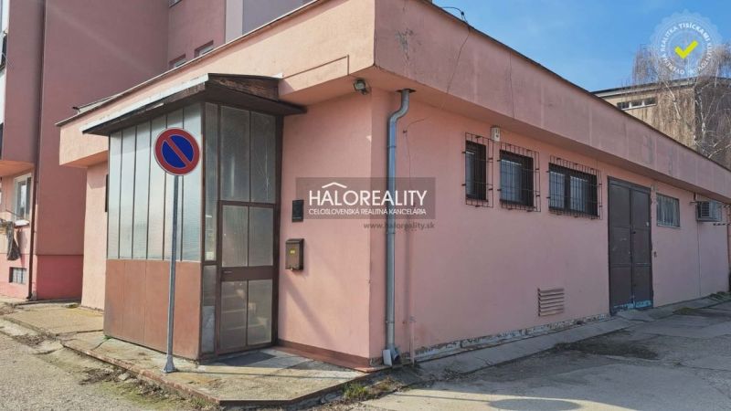 Exteriér budovy kanceláří v Senci se zákazovou značkou parkování a plechovými dveřmi.
