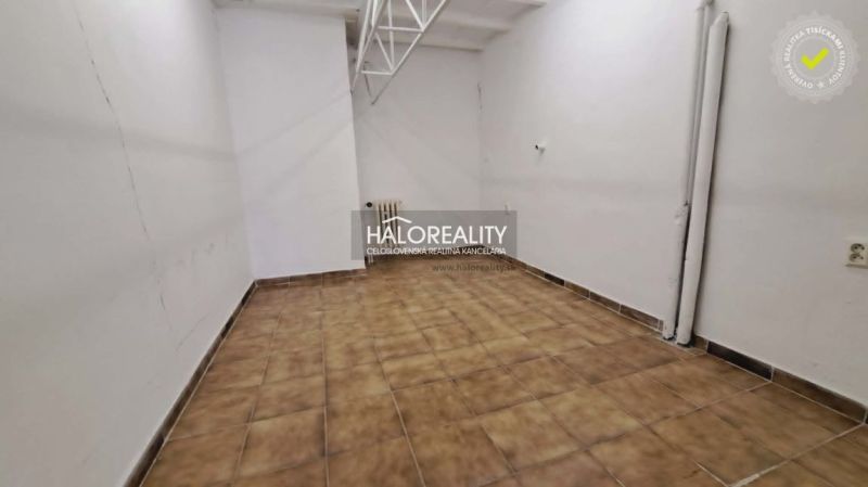 Interiér kanceláře s bílými stěnami a hnědou dlažbou.