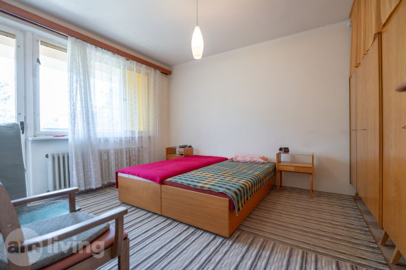 Ložnice se světlým kobercem a postelí v 3pokojovém bytě.