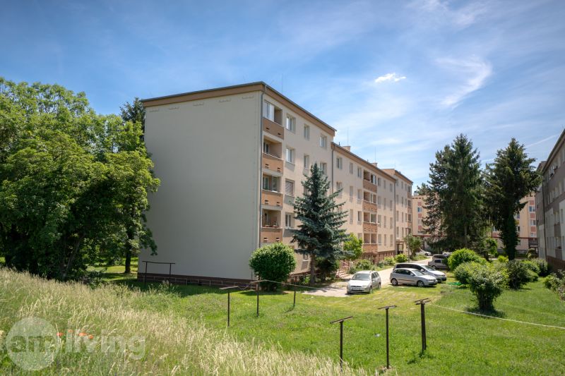Bytové domy na ulici Švermova v Trenčíně s okolní zelení a zaparkovanými auty.