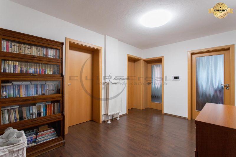 Interiér rodinného domu s dřevěnou dekorací podlahy a knihovnou.