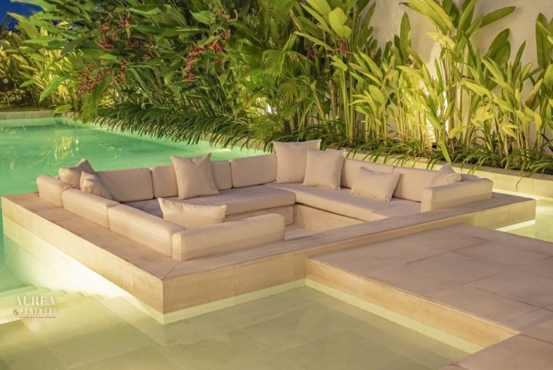 Luxusní venkovní sedačka obklopená tropickou zelení u bazénu ve vile na Bali.