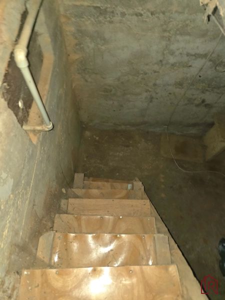 Schodiště vedoucí do sklepa se stěnami s viditelnými trubkami v Zahradách.