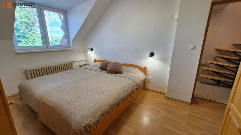 Ložnice v 2-pokojovém bytě s manželskou postelí a podlahou s dřevěným dekorem.