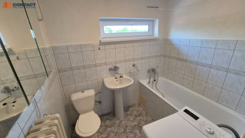 Koupelna v 2-pokojovém bytě s vanou, umyvadlem, pračkou a obloženými stěnami.